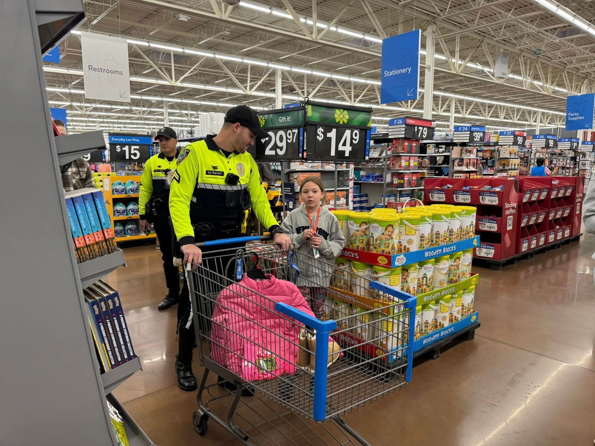 A man is pushing a shopping cart with a girl in it in a store.