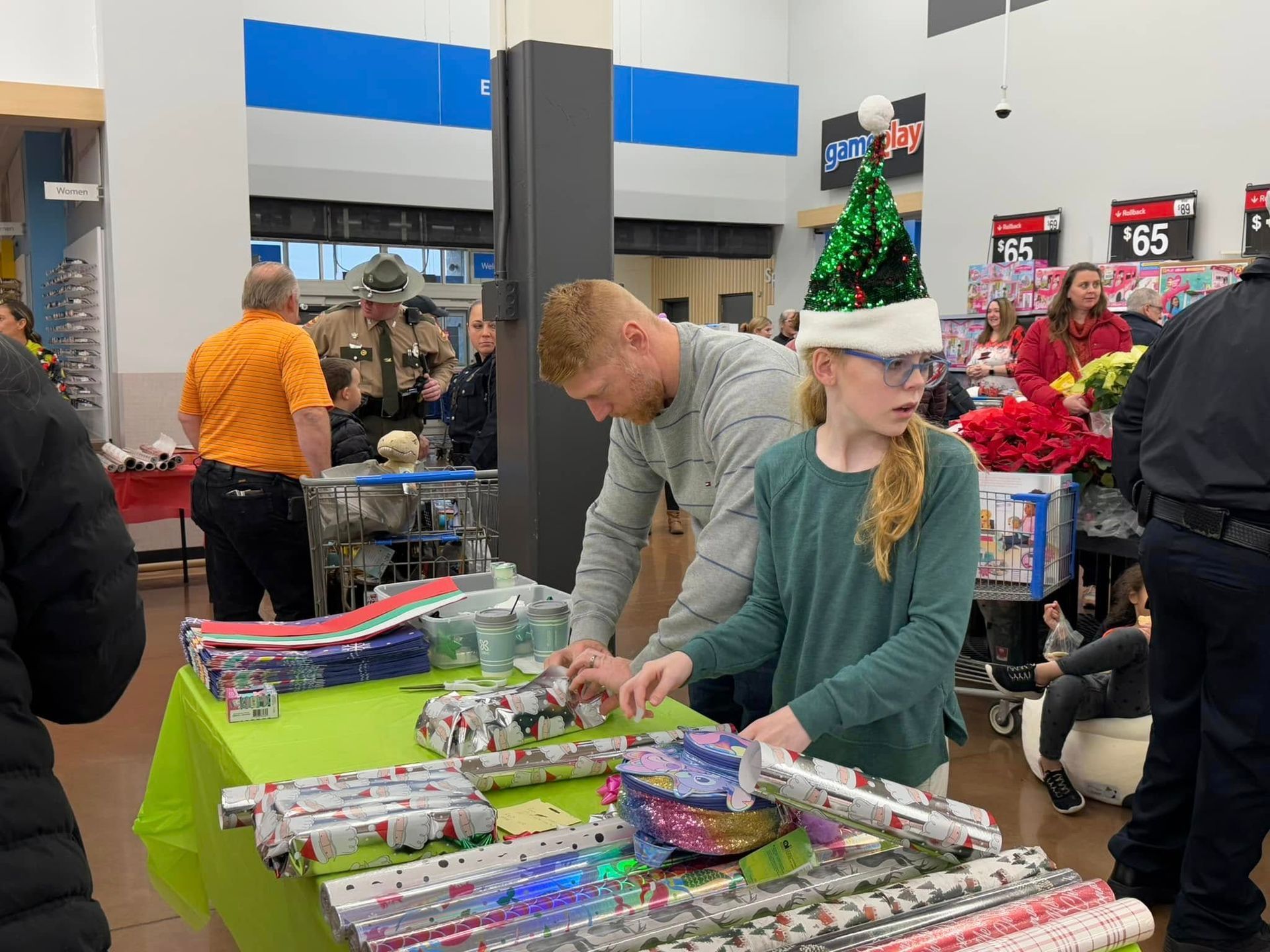 A man and a girl are wrapping gifts at a table in a store.