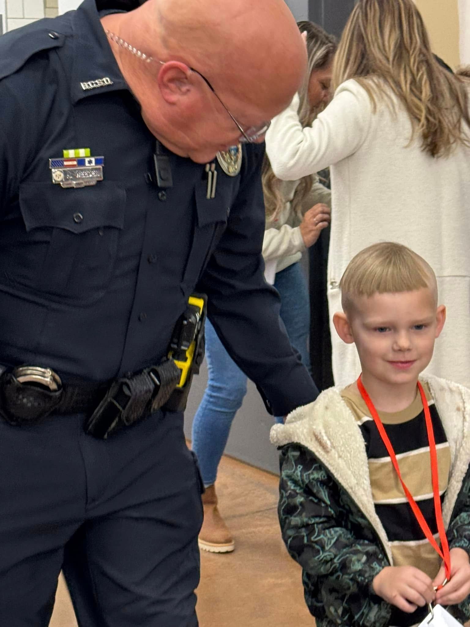 A police officer is standing next to a little boy.