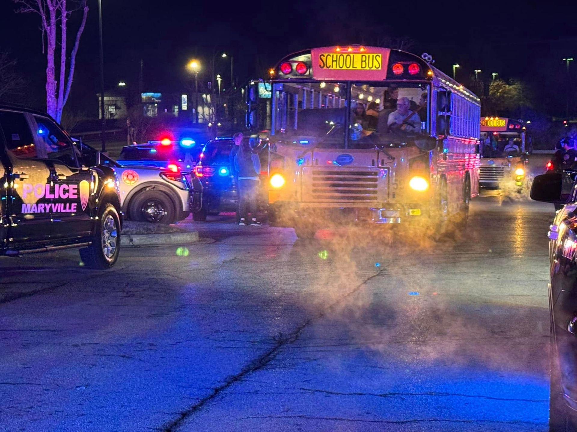 A school bus is driving down a street at night.