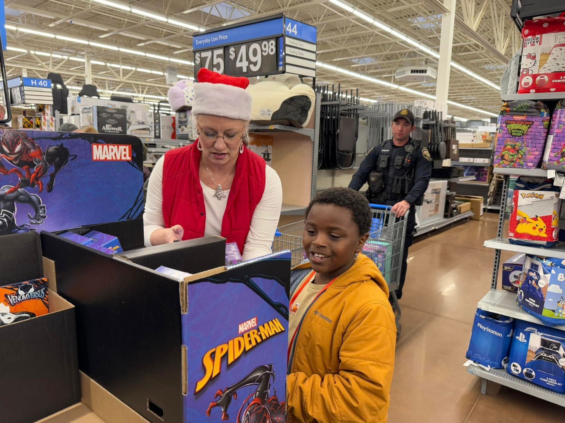 A woman in a santa hat is talking to a boy in a store.