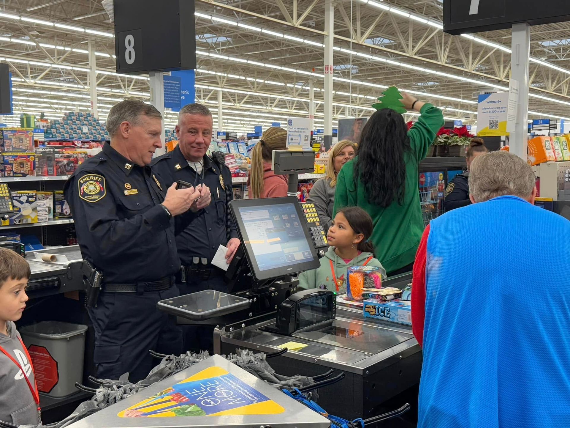 A group of people are standing around a cash register in a store.