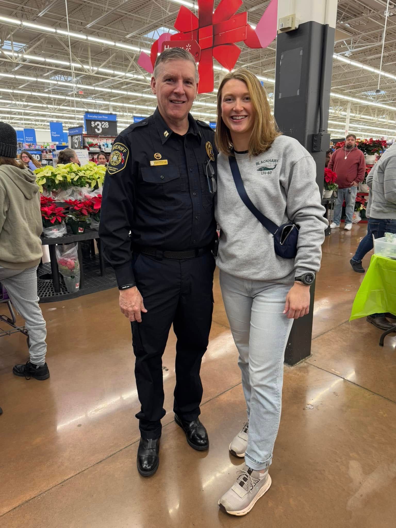 A police officer and a woman are posing for a picture in a store.