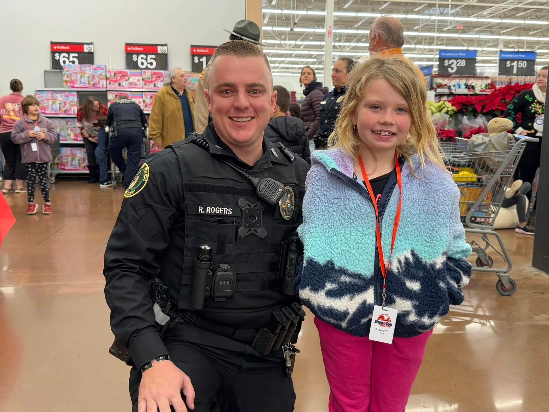 A police officer and a little girl are posing for a picture in a store.
