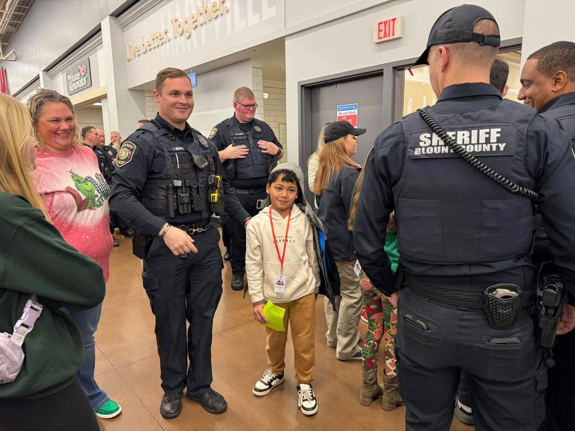 A group of police officers are standing next to each other in a store talking to a little girl.