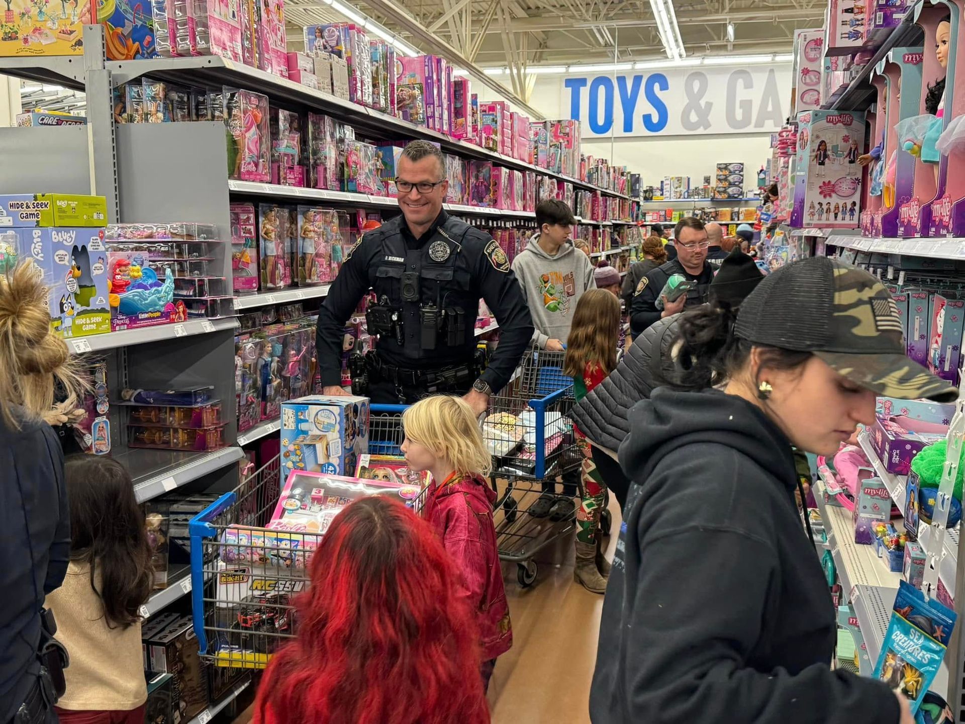 A police officer is standing in a toys and games section of a store.