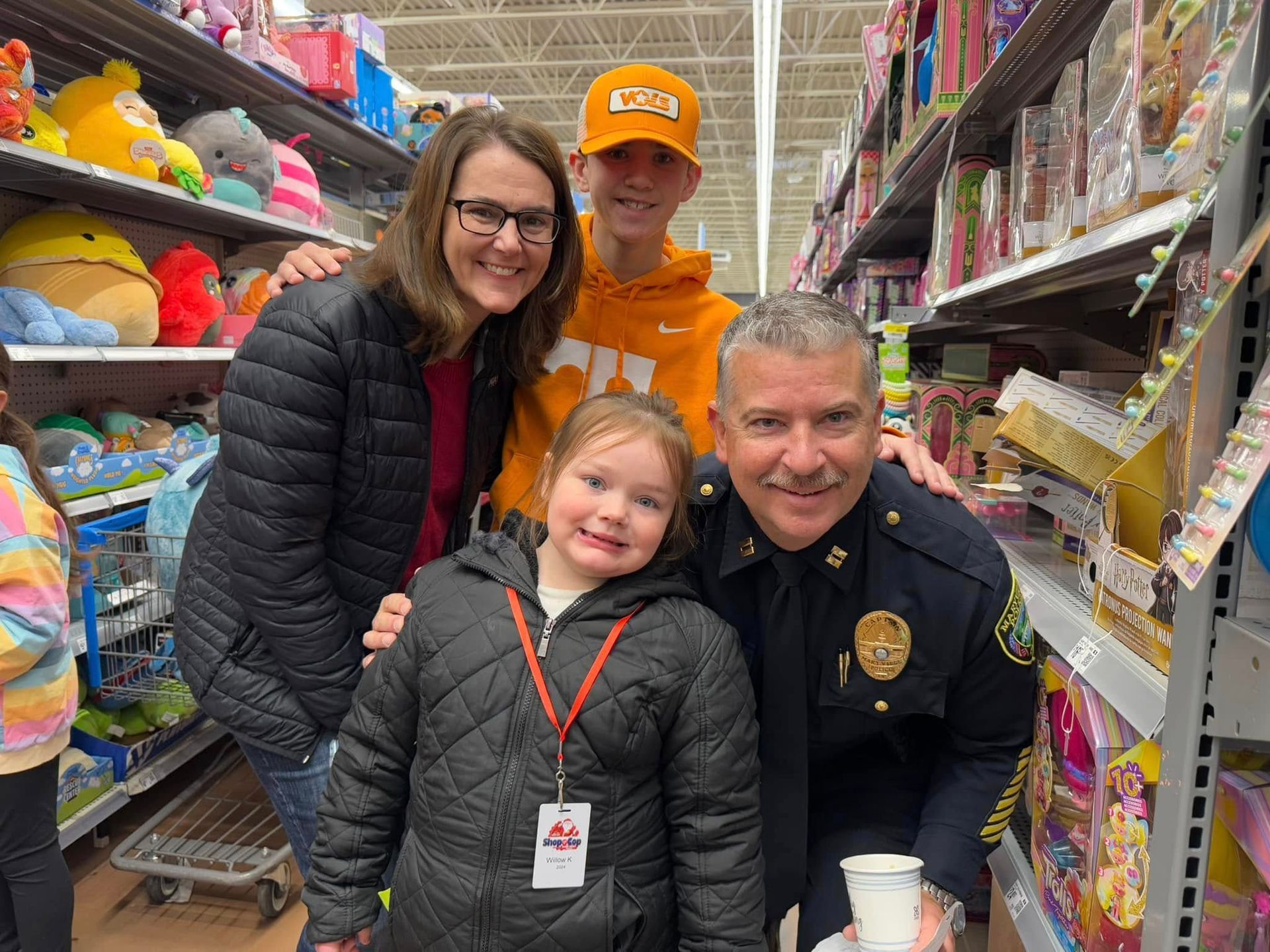 A police officer is posing for a picture with a family in a store.