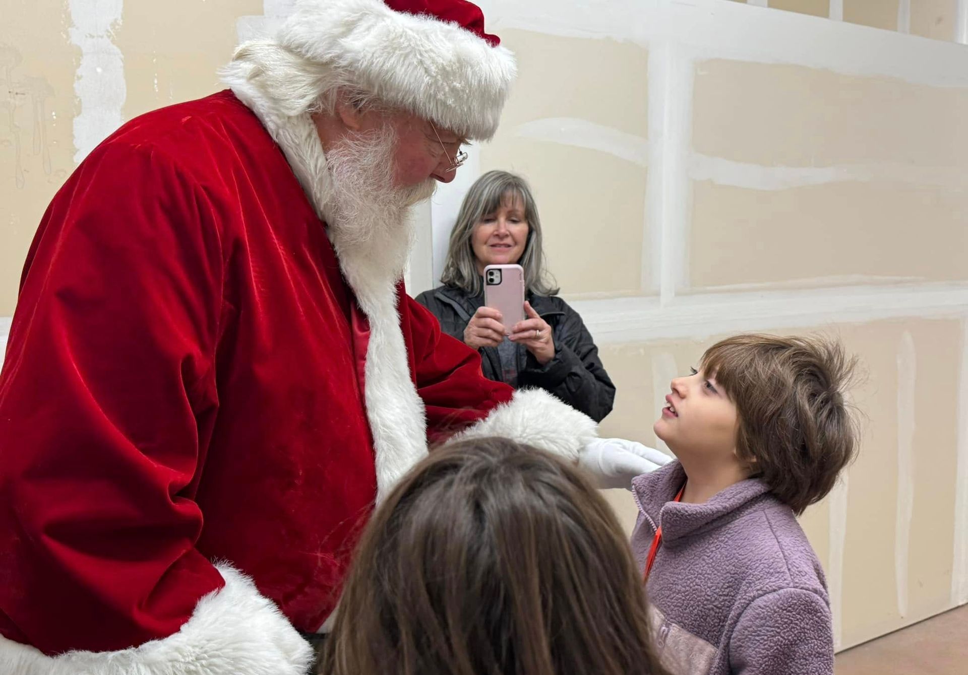 A police officer and a little boy are posing for a picture with santa claus in a store.