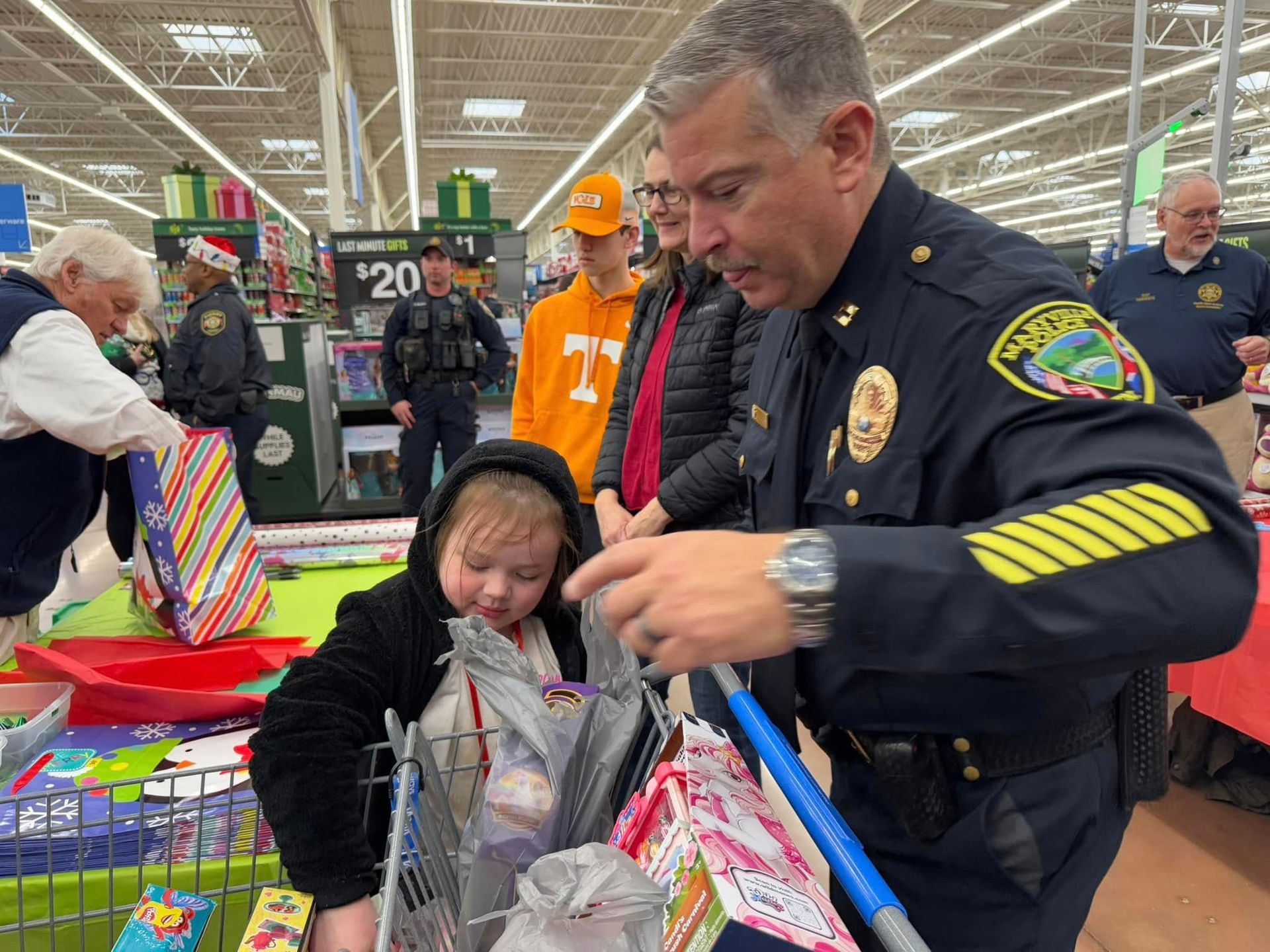 A police officer is helping a little girl in a shopping cart.