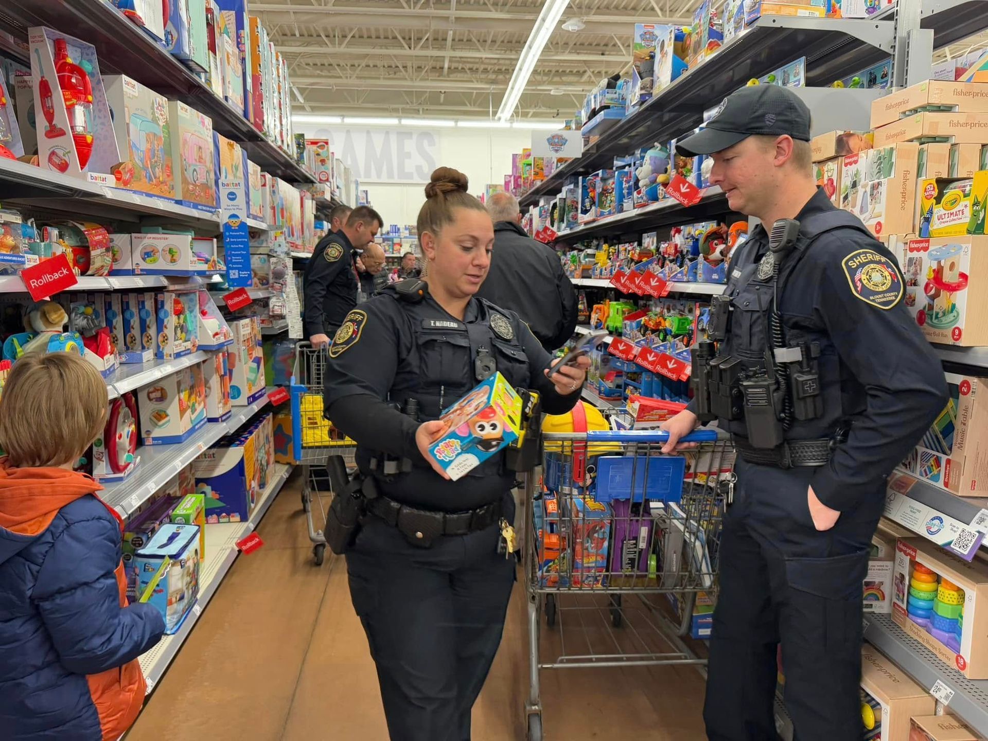Two police officers are standing next to each other in a store looking at toys.
