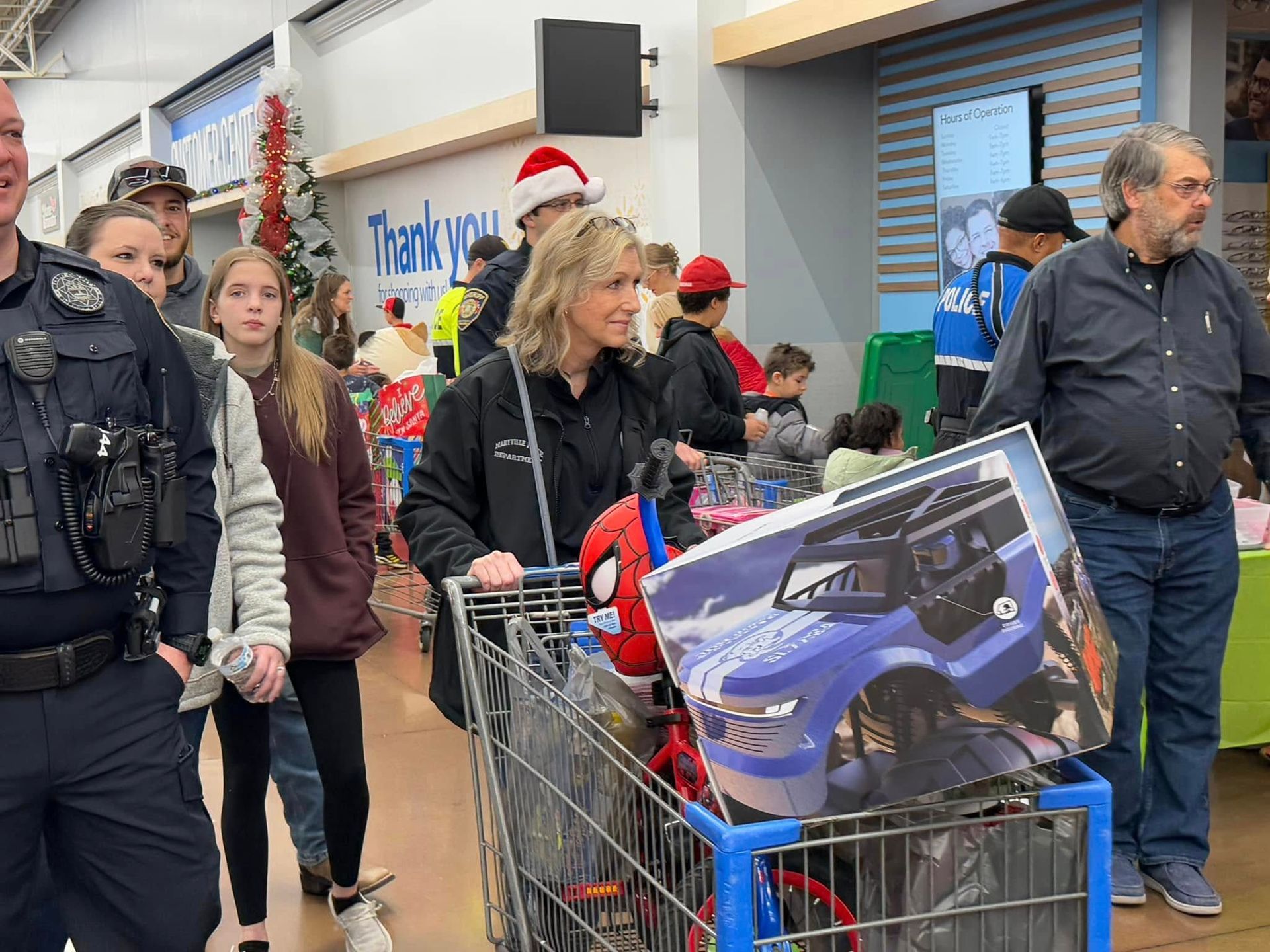 A woman is pushing a shopping cart full of toys in a store.