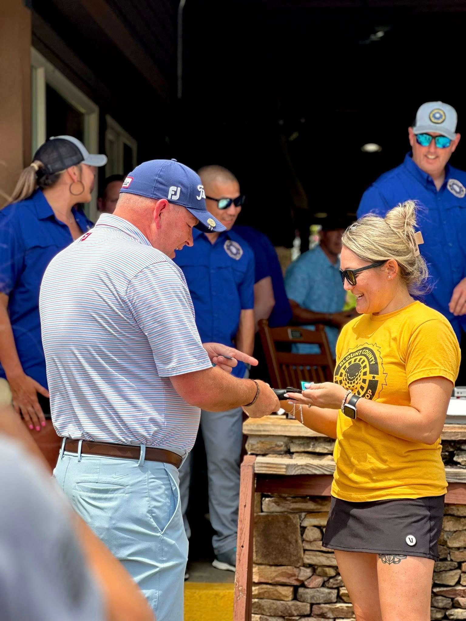 A man in a blue hat is talking to a woman in a yellow shirt.