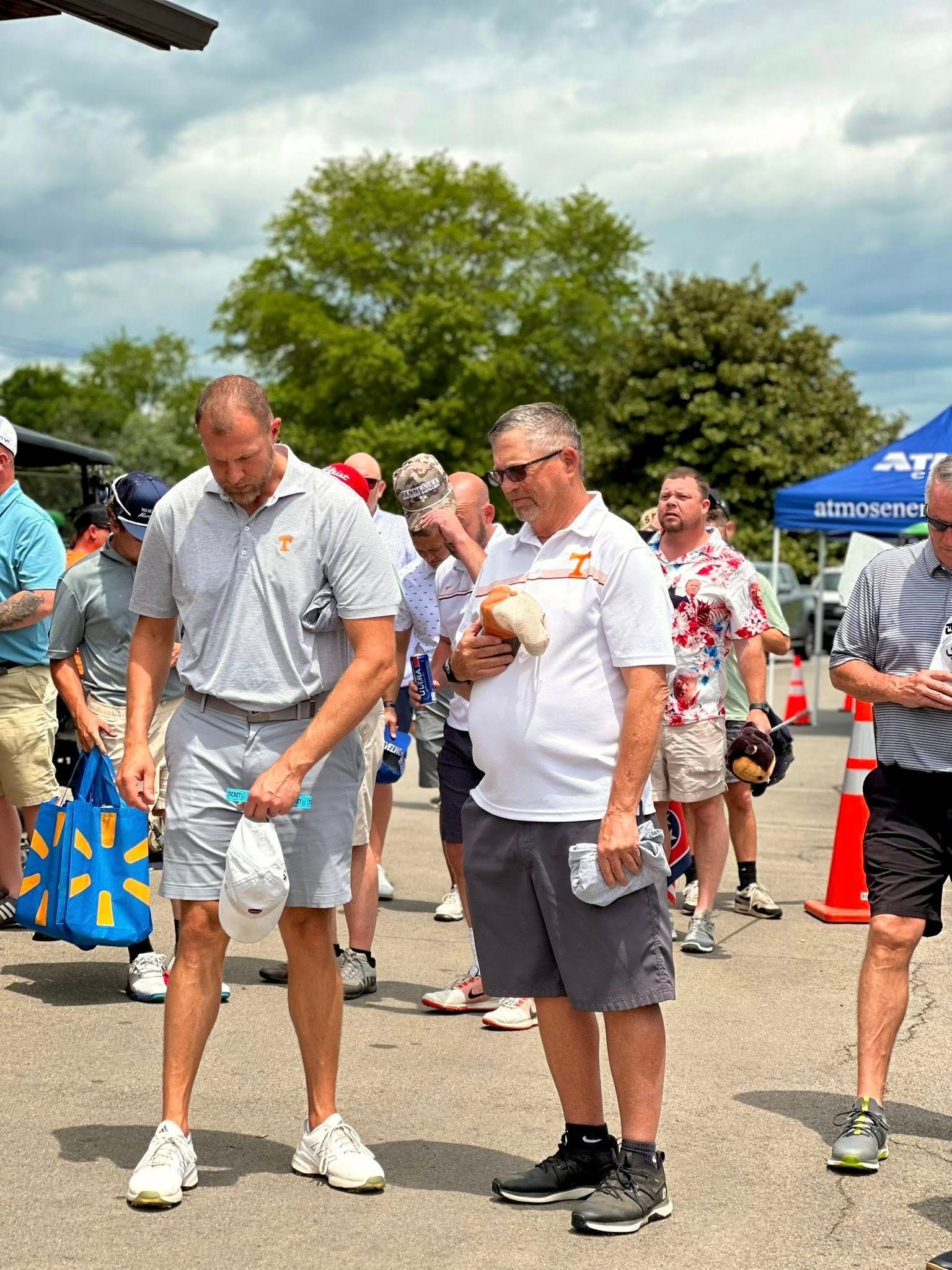 A group of men are standing in a parking lot talking to each other.