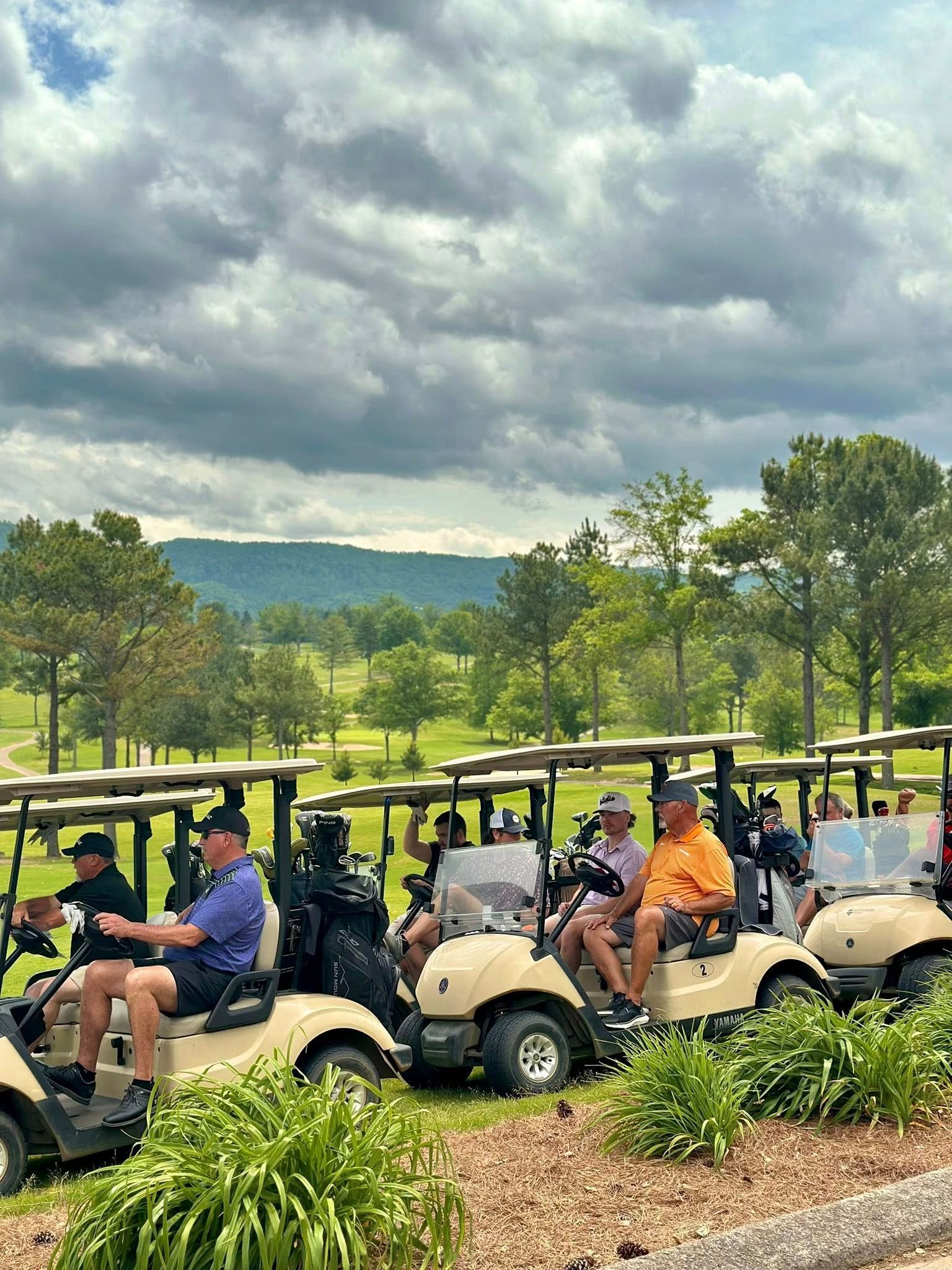 A group of people are riding golf carts on a golf course.
