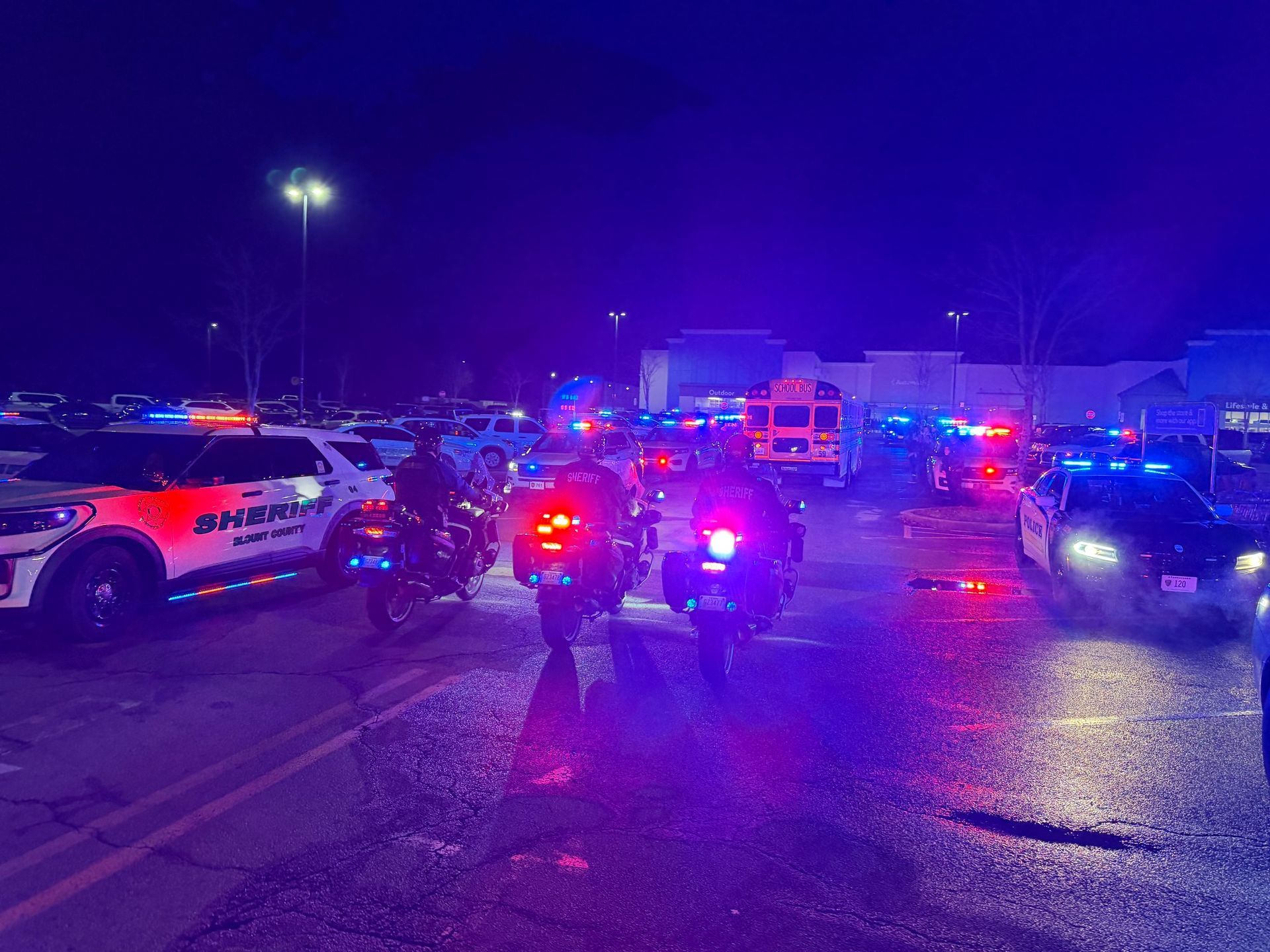 Police vehicles with flashing lights at night in a parking lot.