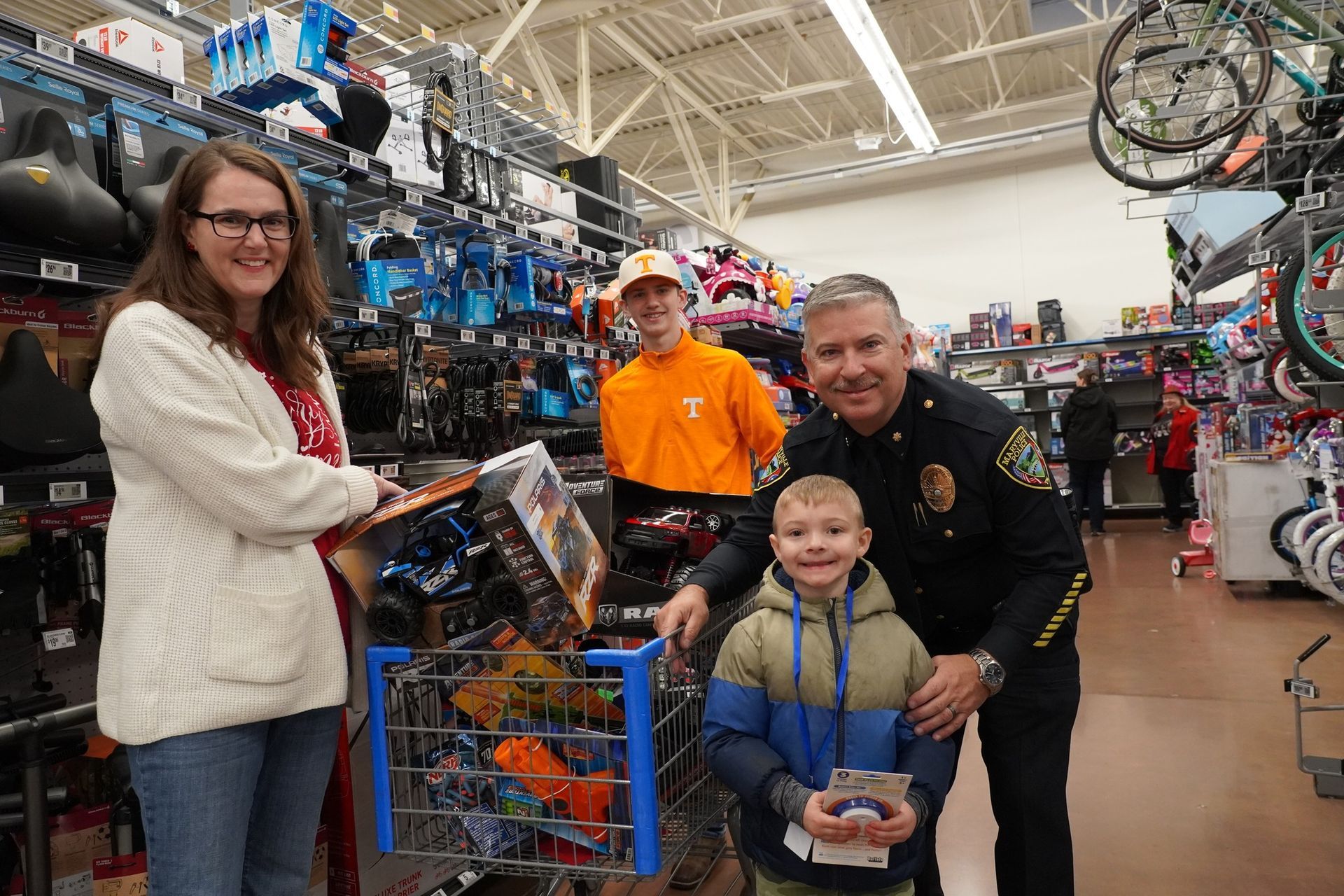 A police officer and a child are talking to santa claus in a store.