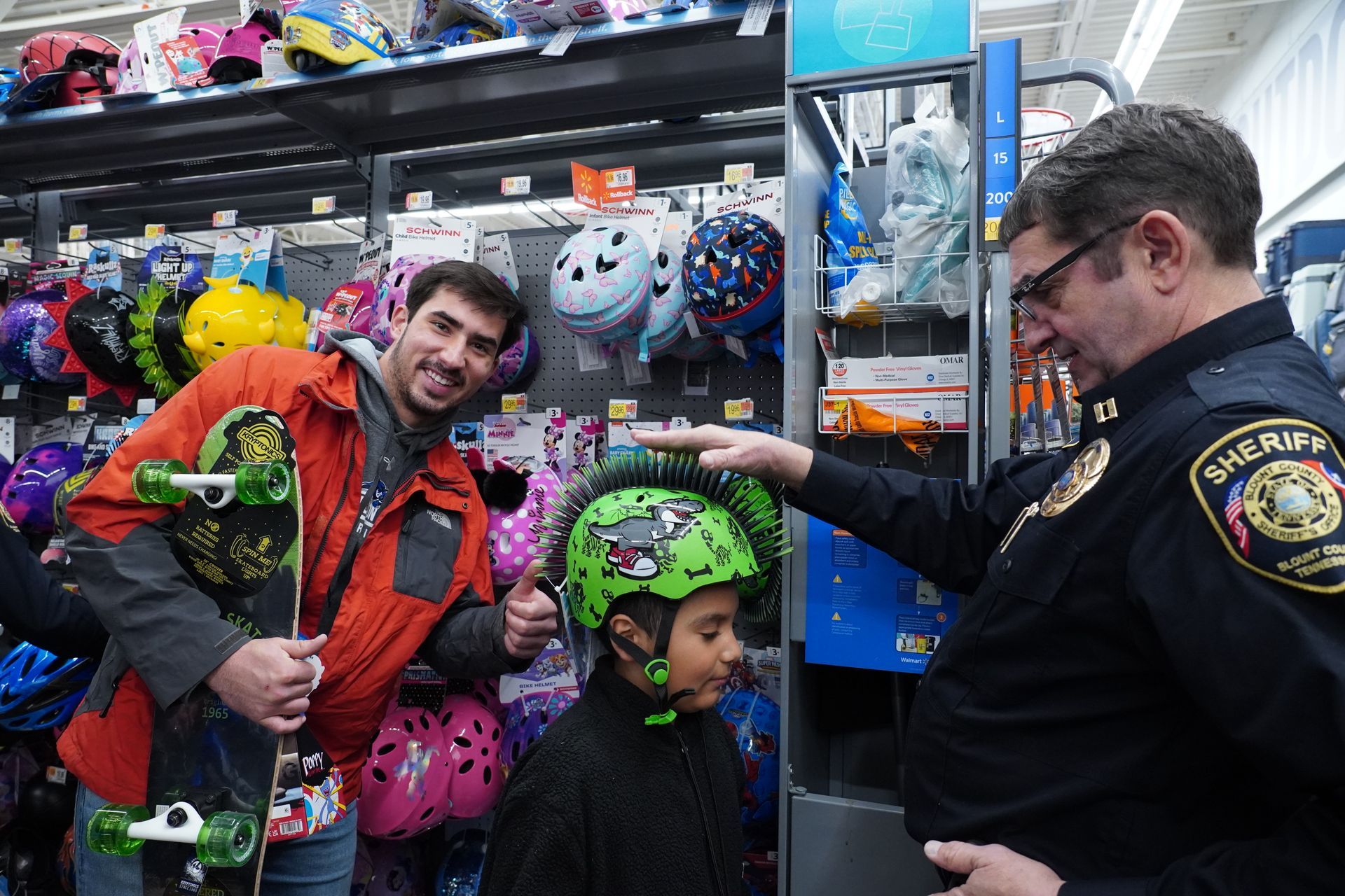A man is holding a skateboard and a child is wearing a helmet.
