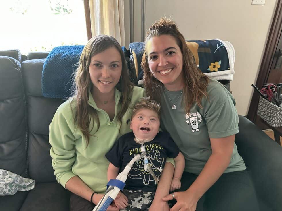 Two women and a child are posing for a picture on a couch.