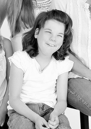 Woman and child smiling on a swing set. Woman wearing glasses, child with curly hair. Outdoors, sunny day.