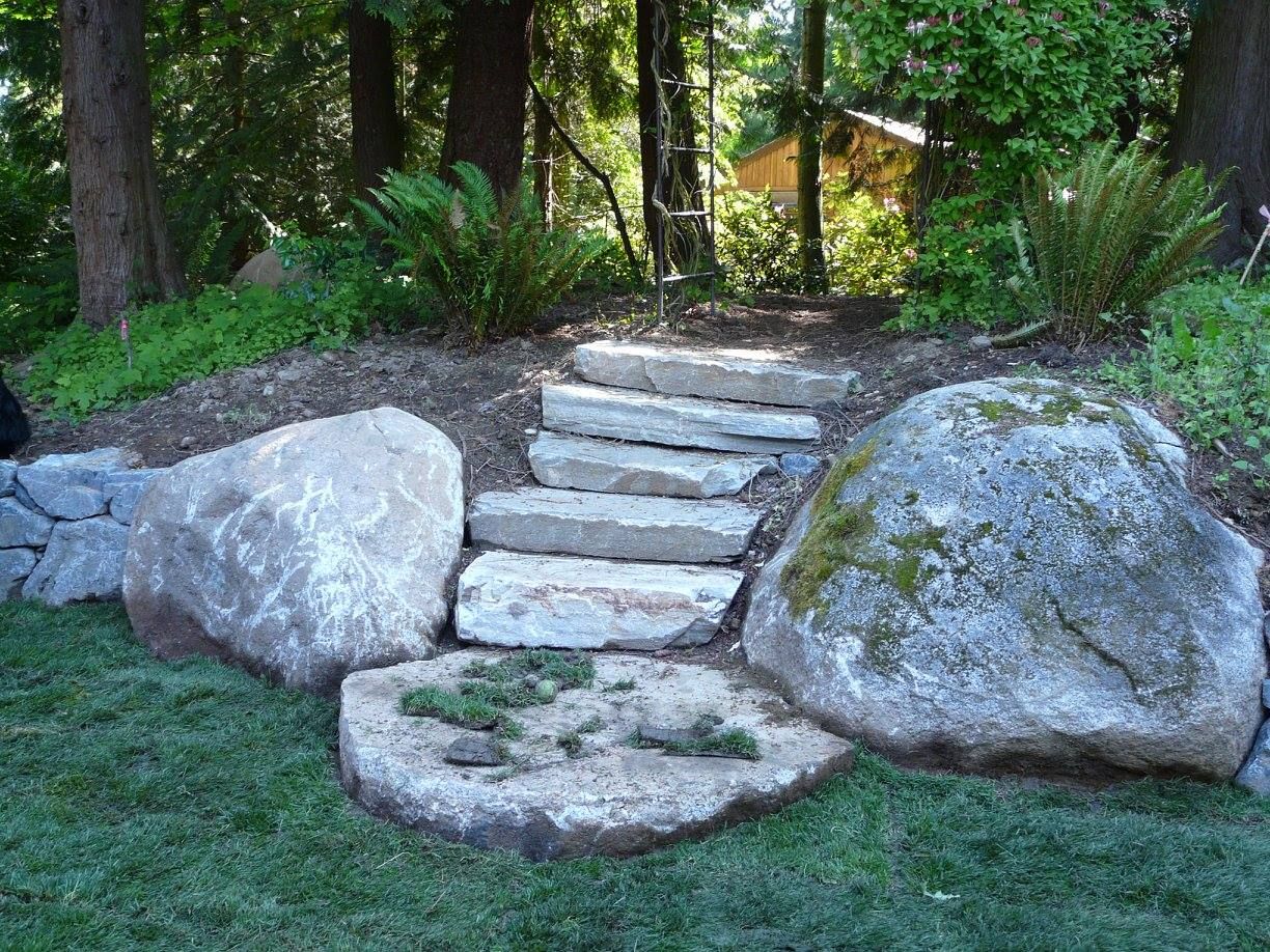 A stone walkway surrounded by large rocks in a garden.