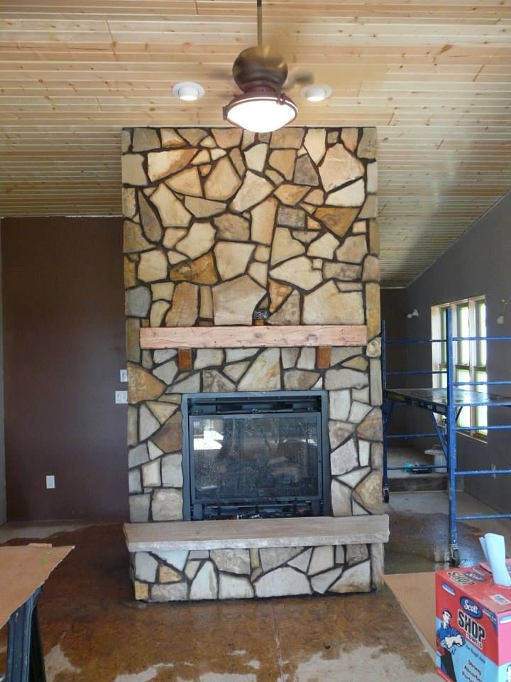 A stone fireplace with a ceiling fan above it
