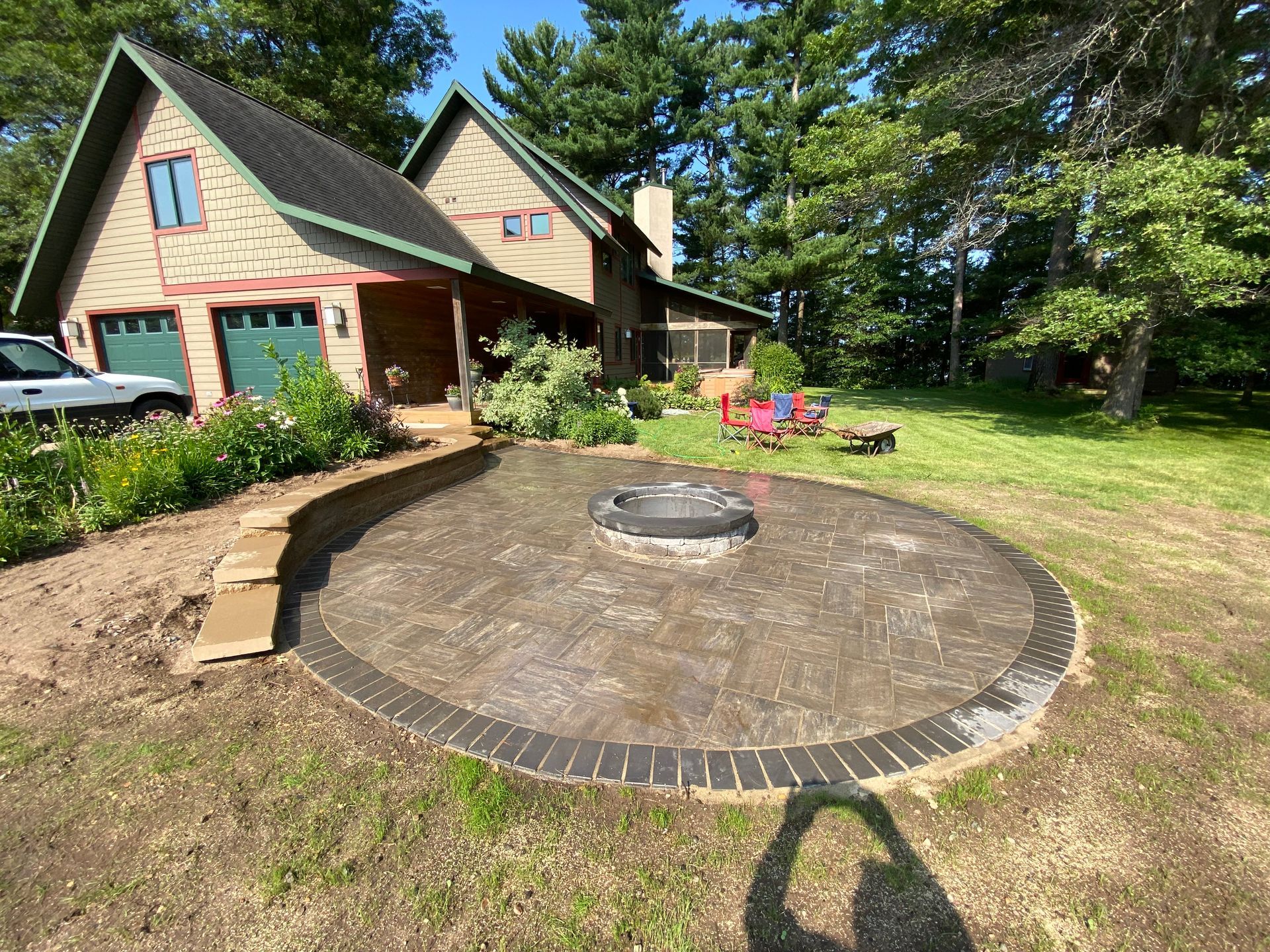 There is a fireplace in the backyard with two chairs in front of it.