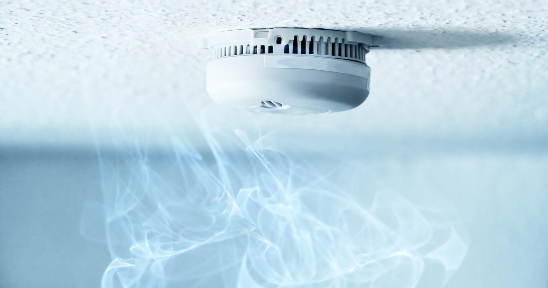 Un détecteur de fumée au plafond avec de la fumée qui en sort.