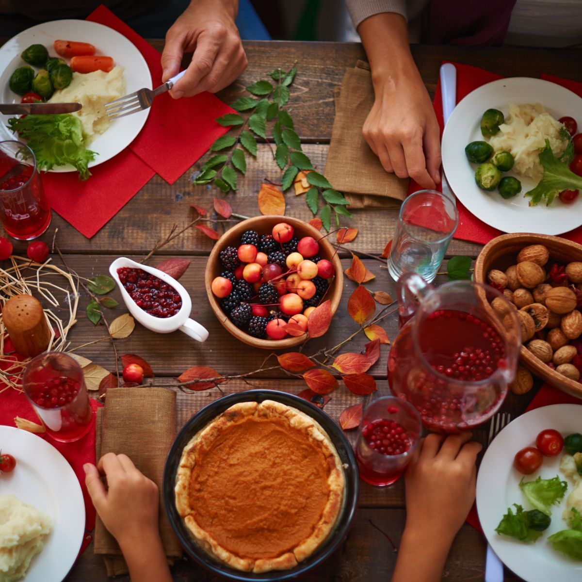 A family is sitting at a table with plates of food and a pumpkin pie.