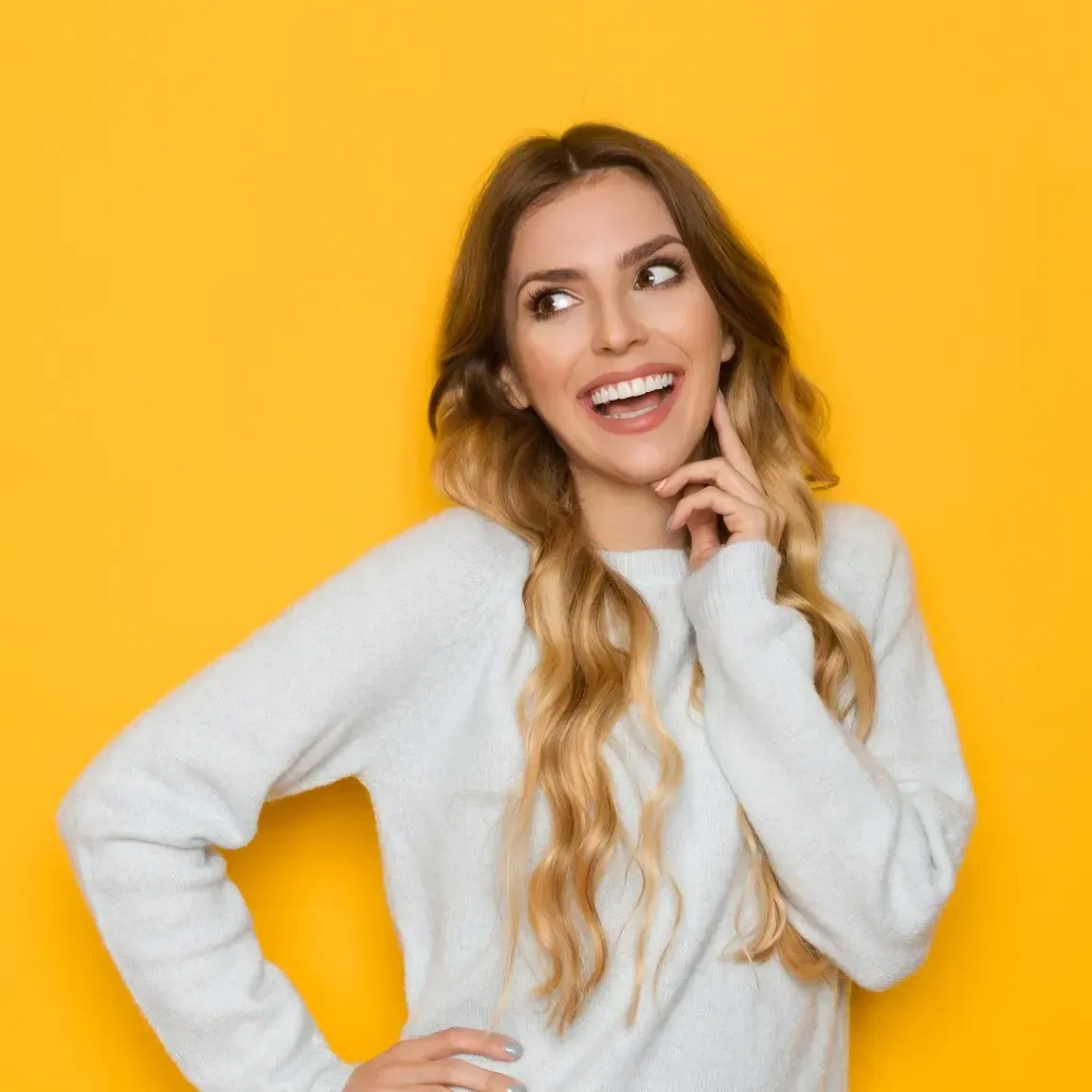 Blonde woman, yellow background, white sweater, smiling