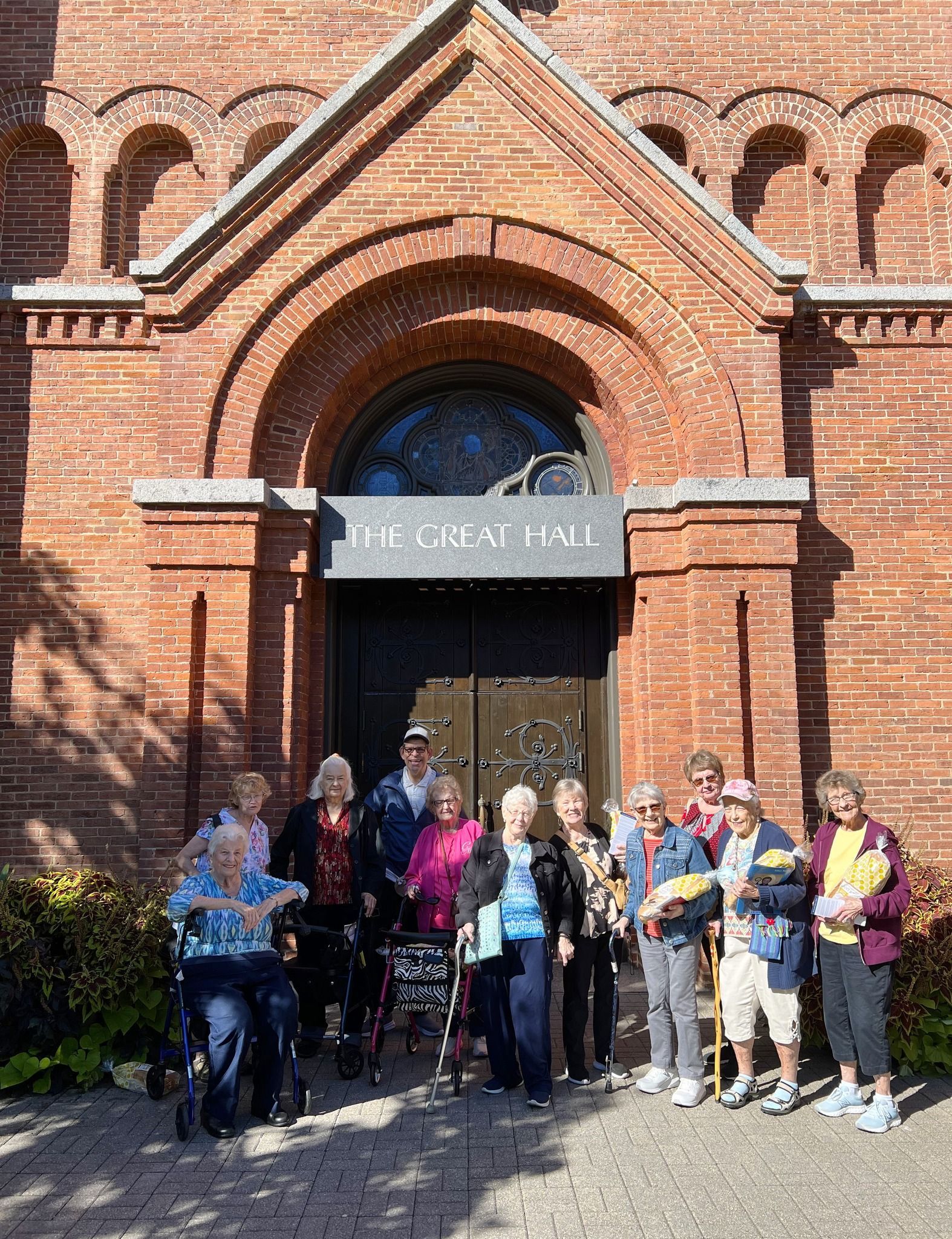 A group of people are standing in front of a brick building.