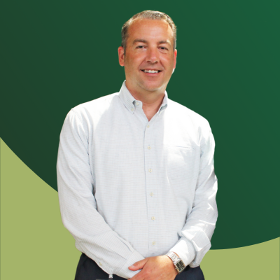 A man in a white shirt is standing in front of a green background