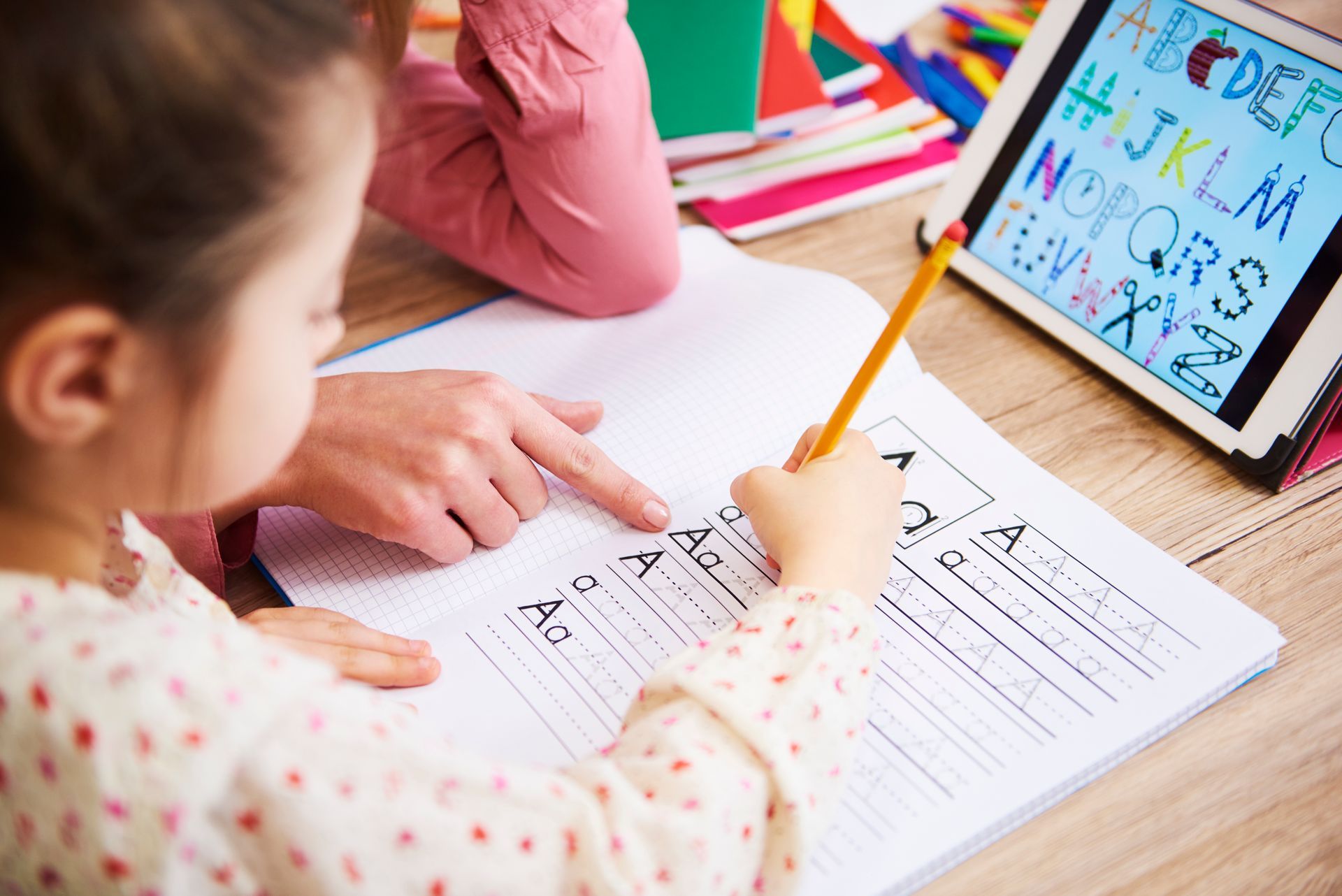 A little girl is sitting at a table writing in a notebook.