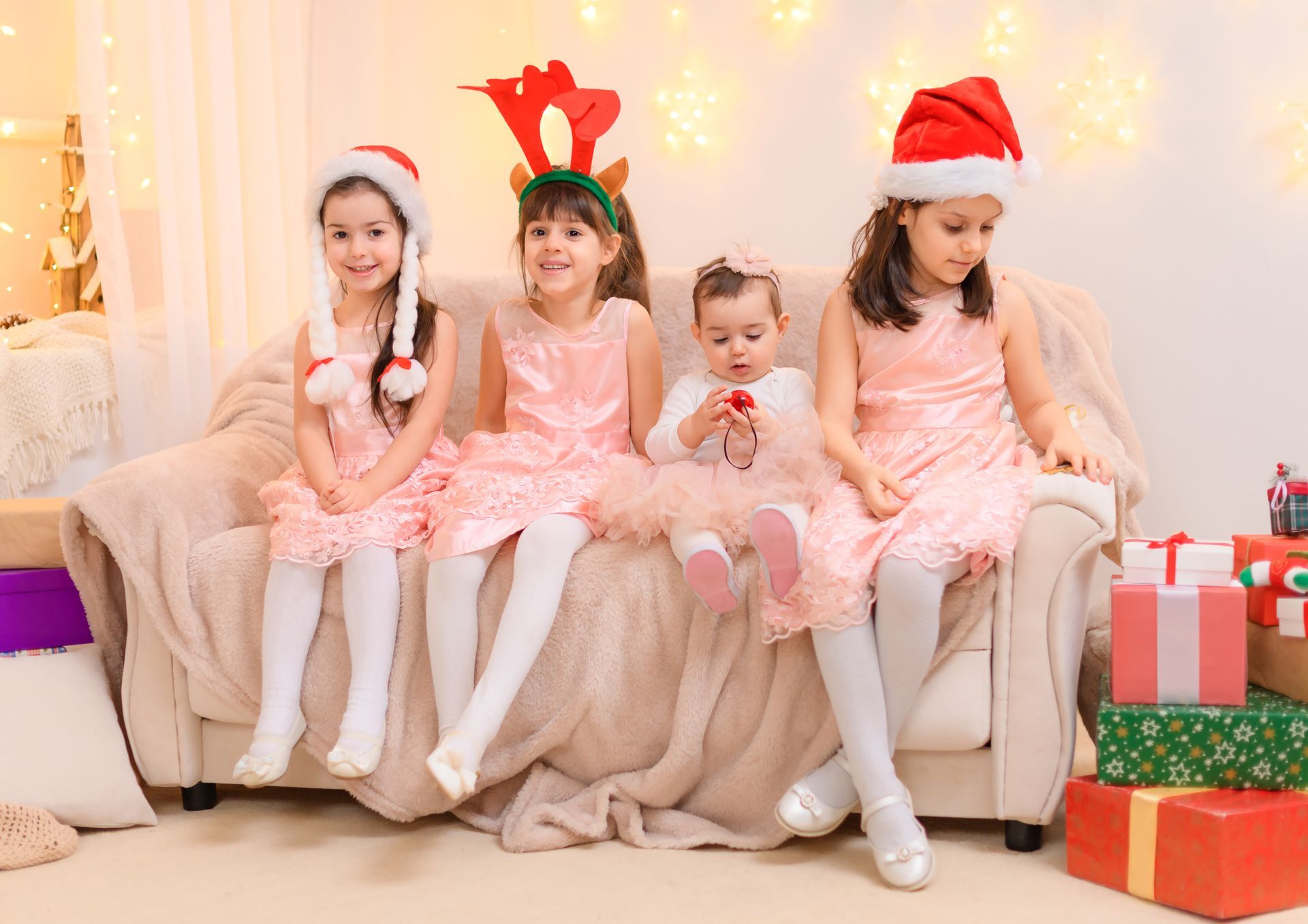 Four little girls are sitting on a couch with christmas presents.