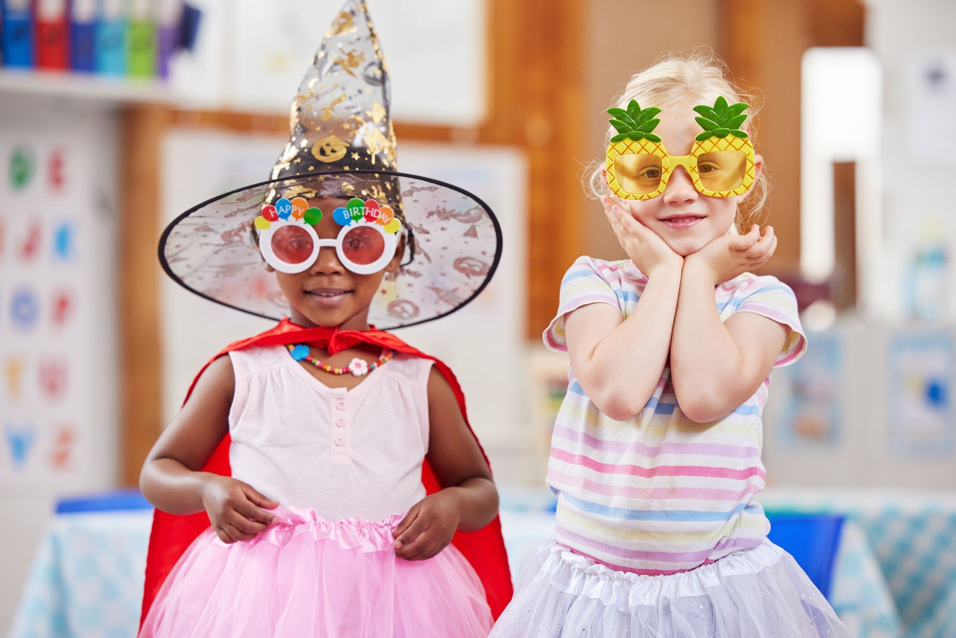 Two little girls are dressed up in costumes in a classroom.