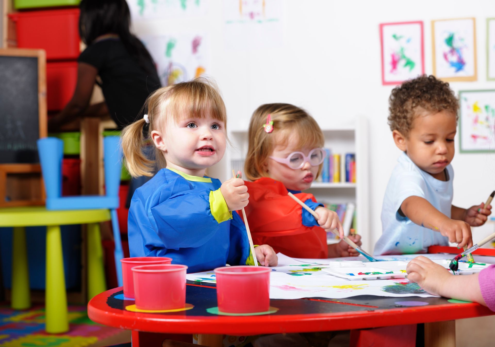 A group of children are sitting at a table painting.