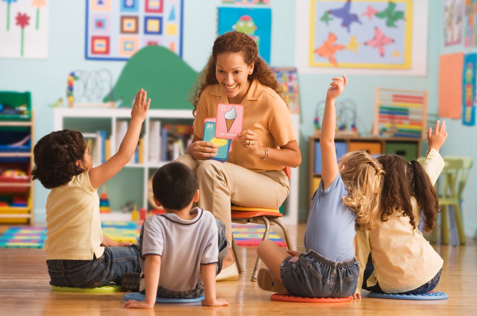 A teacher is reading a book to a group of children in a classroom.