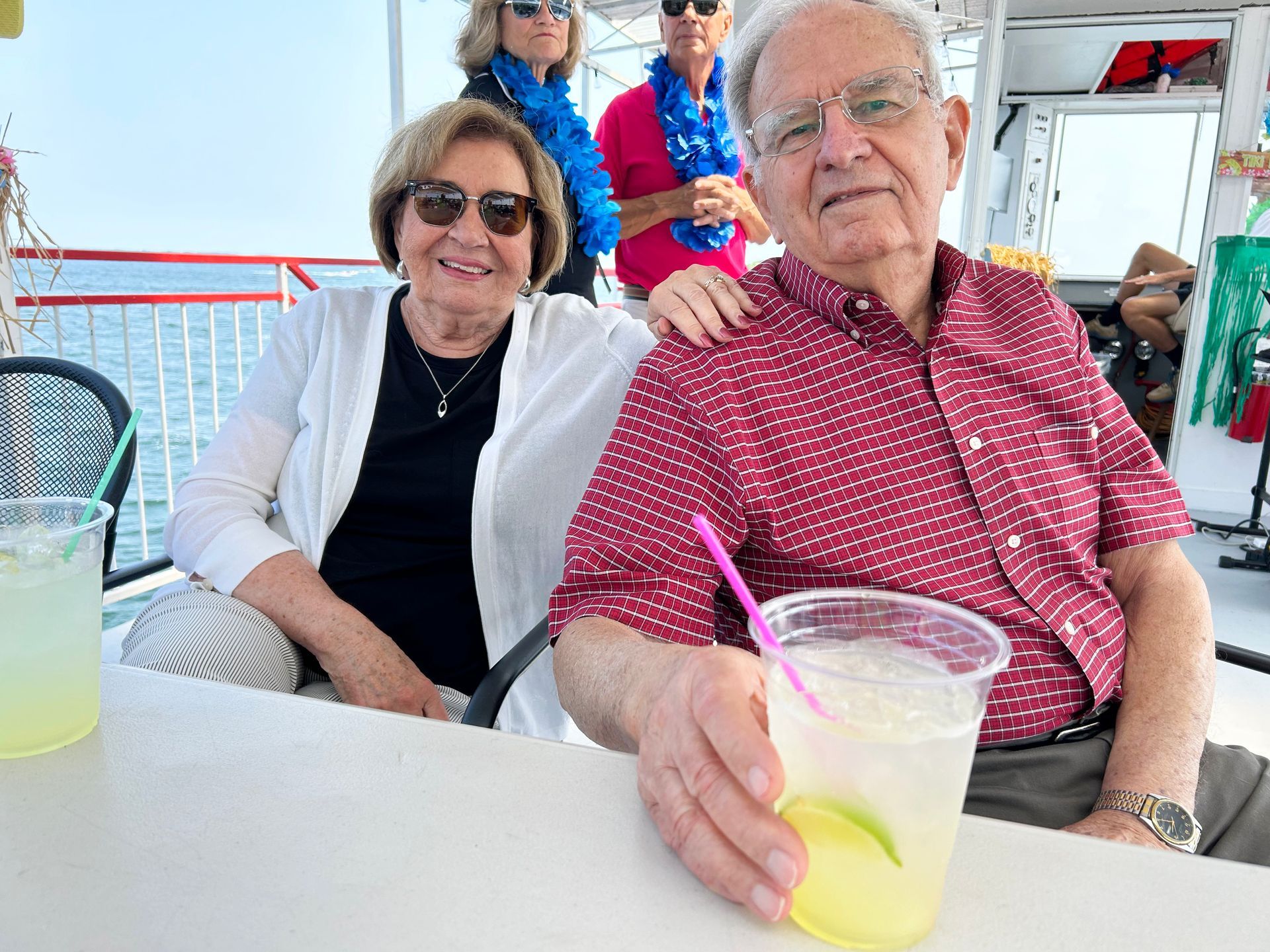 A man and woman are sitting at a table with a drink in their hand.