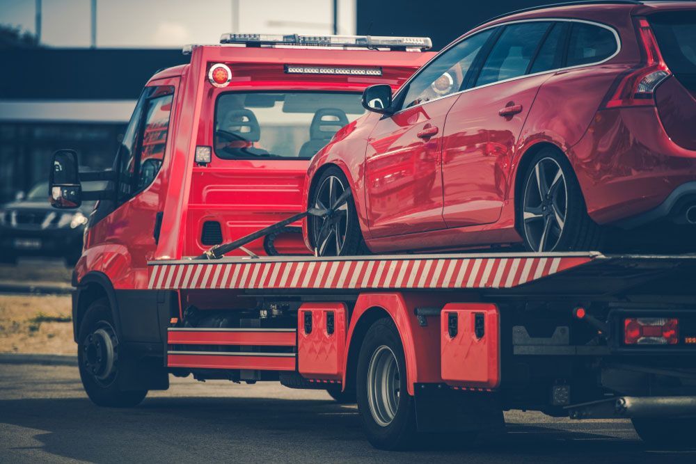 A Red Car Is Being Towed By A Tow Truck — Tim's Towing and Transport In East Maitland, NSW