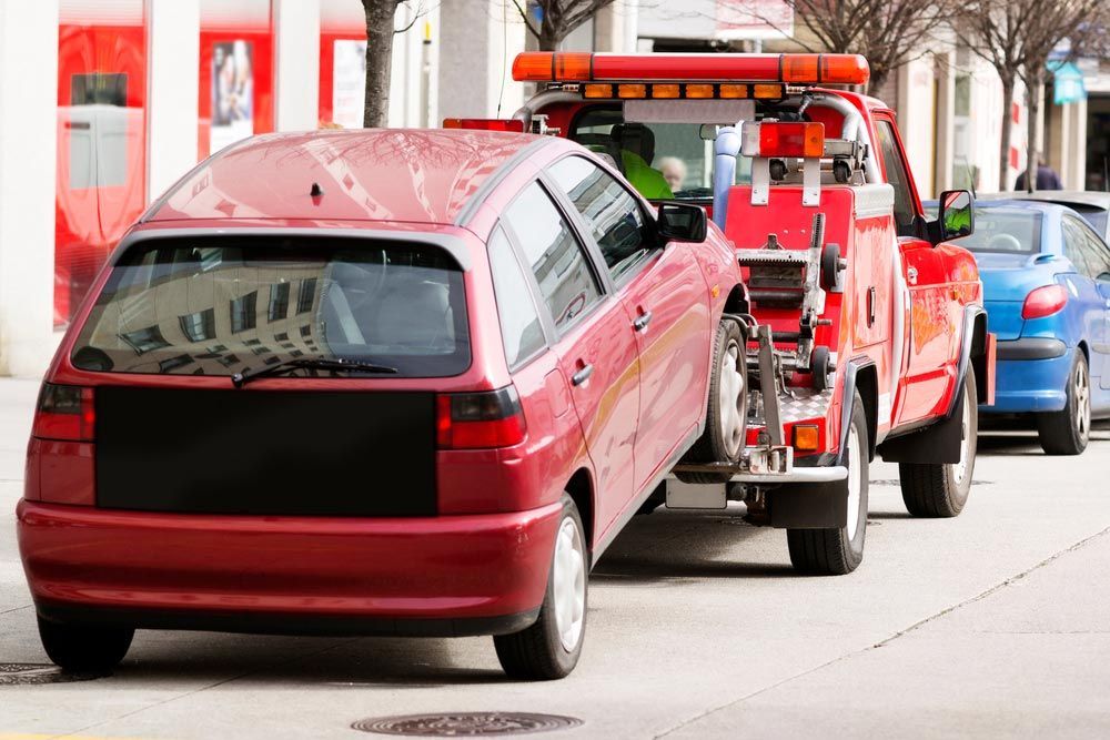 A Red Car Is Being Towed By A Tow Truck — Tim's Towing and Transport In Sandgate, NSW