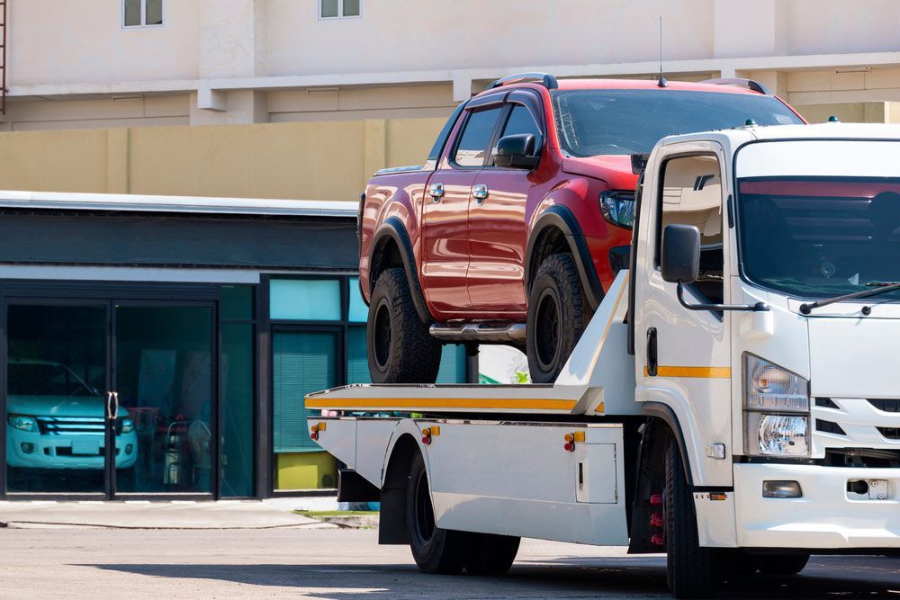 A Red Truck Is Sitting On Top Of A Tow Truck — Tim's Towing and Transport In Mount Thorley, NSW