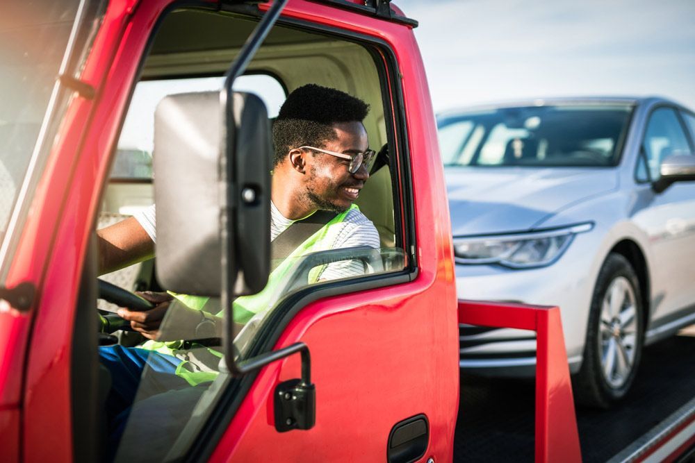 A Man Is Sitting In The Driver's Seat Of A Tow Truck — Tim's Towing and Transport In Belmont, NSW