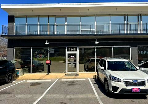 A black, two-story commercial building with an auto service shop on the ground floor and a parking lot in front.