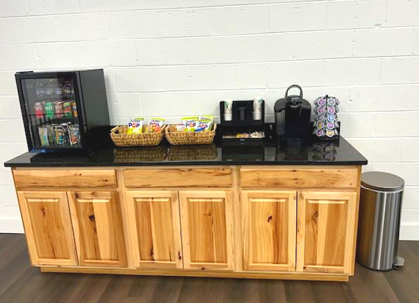 A gray commercial building with a black SUV parked in front, featuring a circular logo and several rectangular windows.