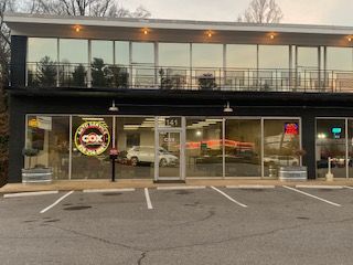 A black, two-story commercial building with an auto service shop on the ground floor and a parking lot in front.