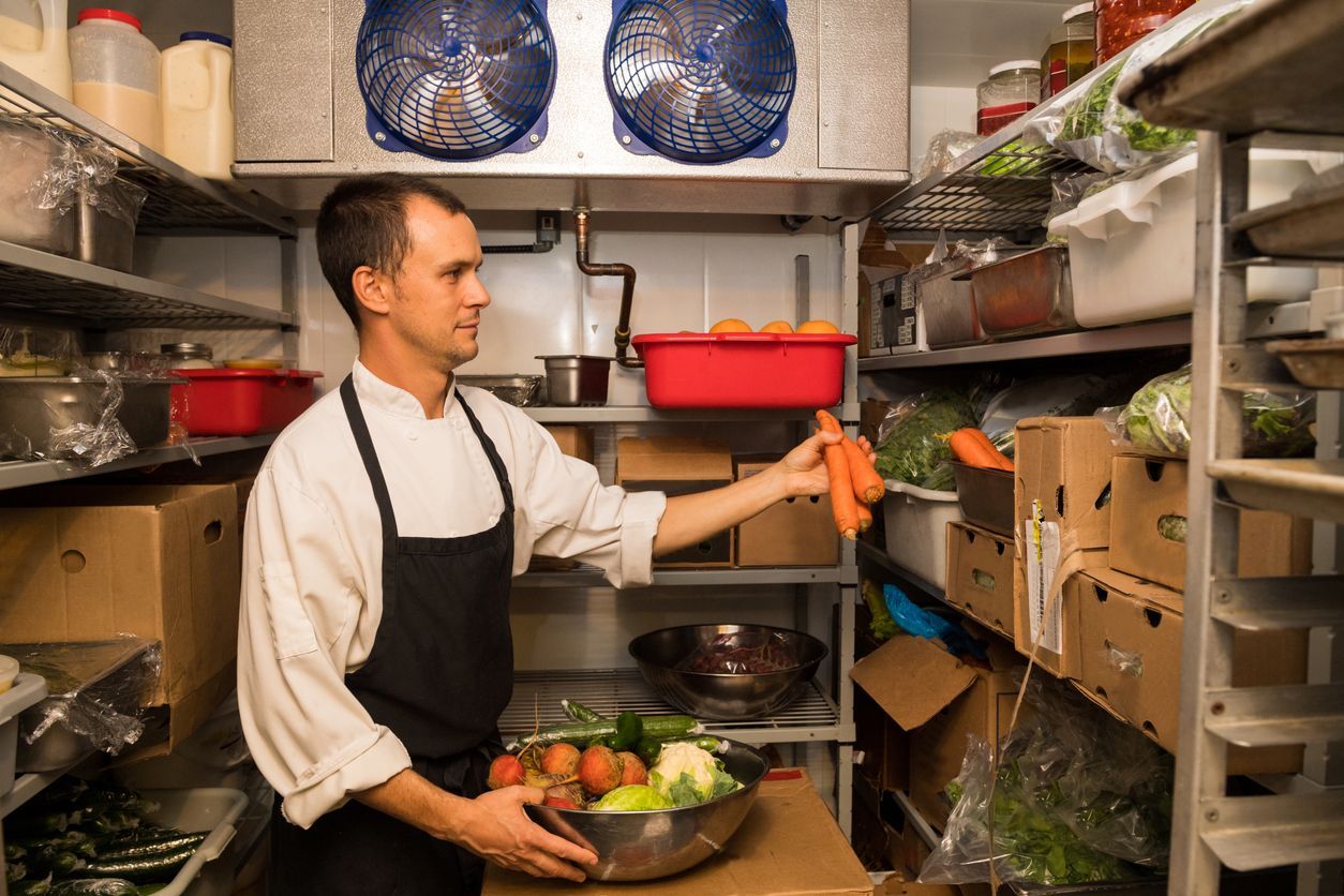 Professional chef at work in a commercial refrigerator.