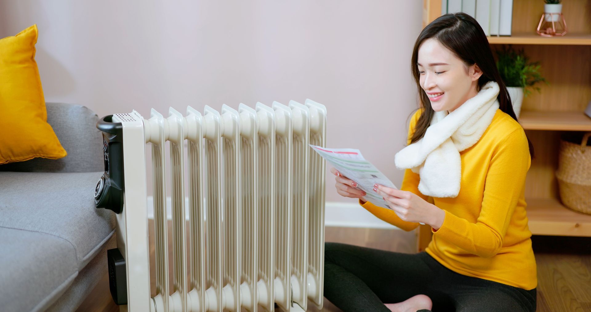 Woman sitting next to a space heater looking at ductless heater options from Reliable Heating & Cool