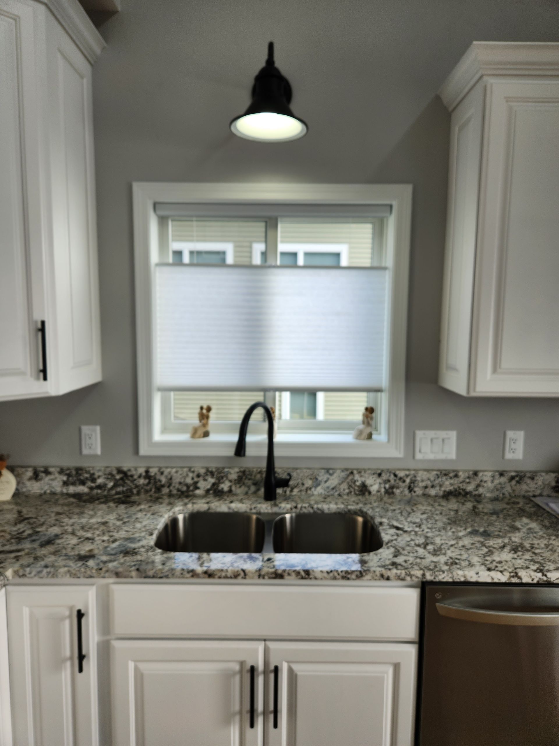 Kitchen with white cabinets, granite countertops, and a window above the sink.