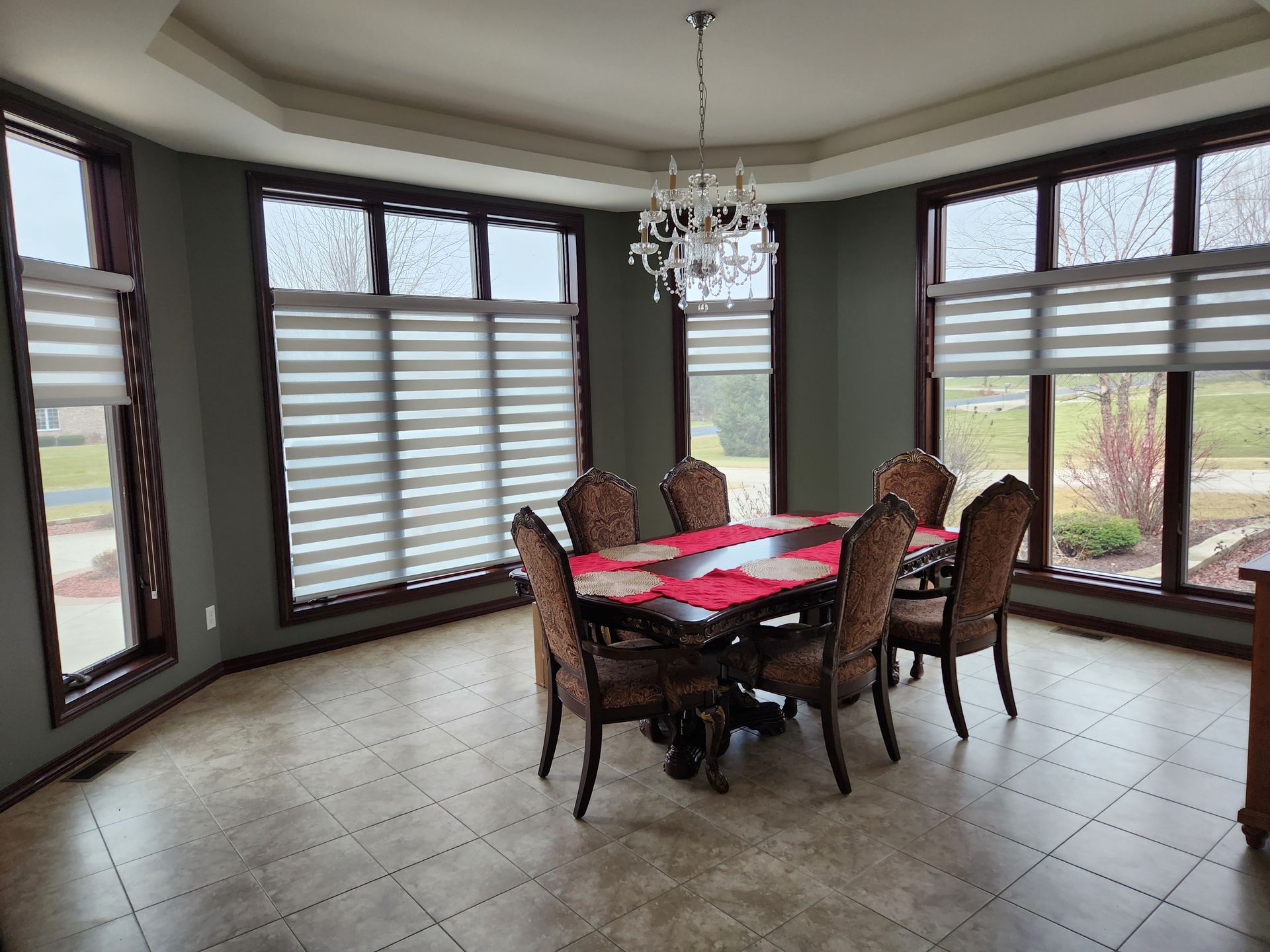 Dining room with bay windows, table set for eight, chandelier.