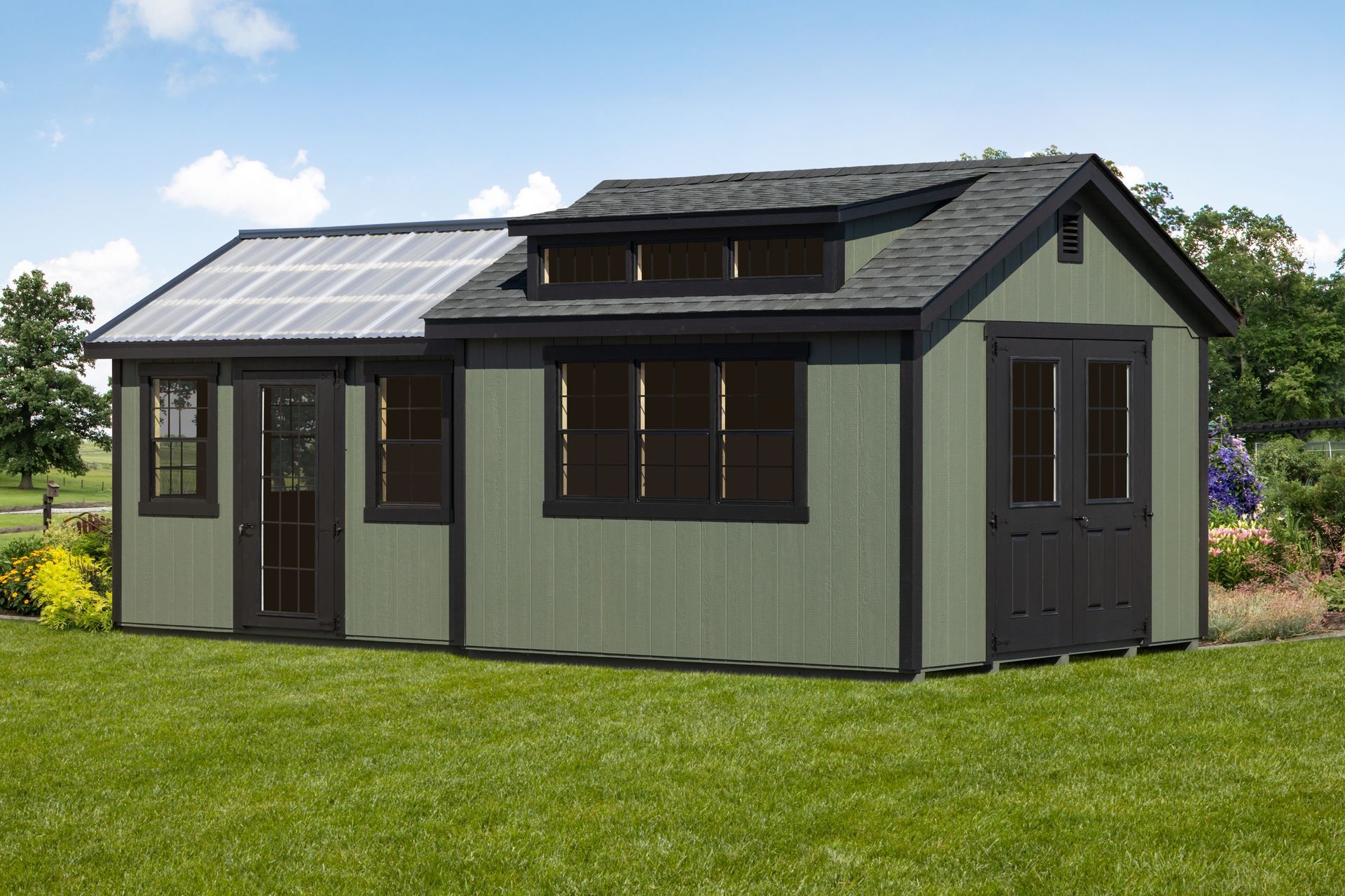 A white shed with a black roof is sitting in the middle of a lush green field.