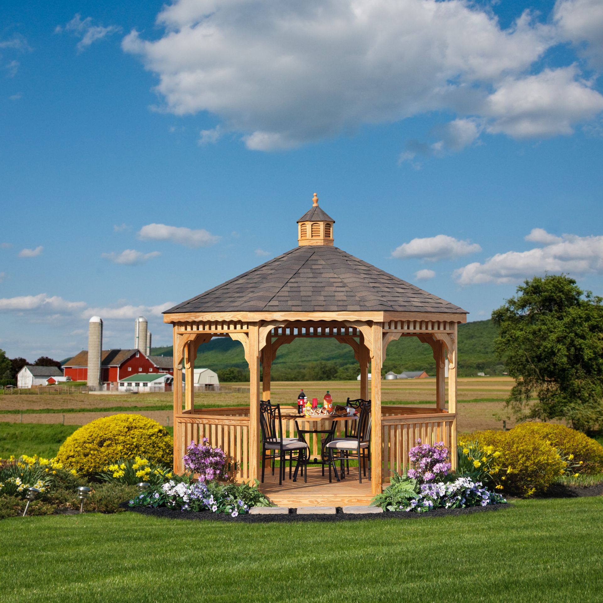 a gazebo with a table and chairs in the middle of a grassy field